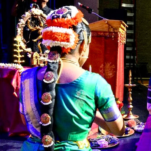 Two women in traditional attire on a stage with decorative elements